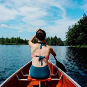 woman riding on boat while paddling under blue sky during daytime